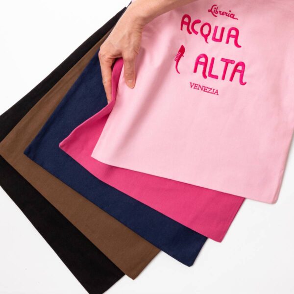 Borsa di tela Libreria Acqua Alta Venezia colore rosa con logo ricamato, tenuta in mano